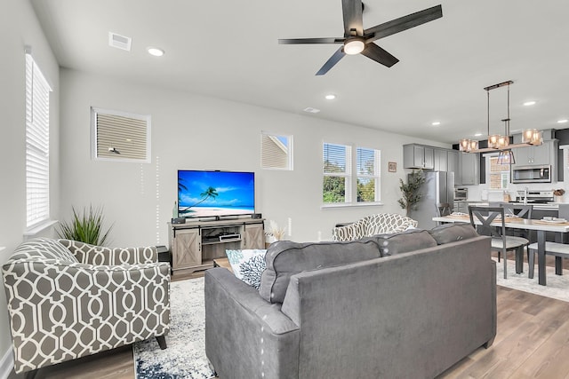 living room featuring dark hardwood / wood-style flooring and ceiling fan with notable chandelier