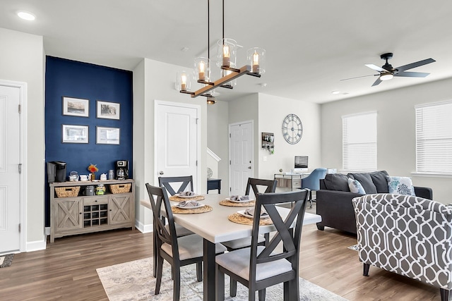 dining area with hardwood / wood-style floors and ceiling fan with notable chandelier