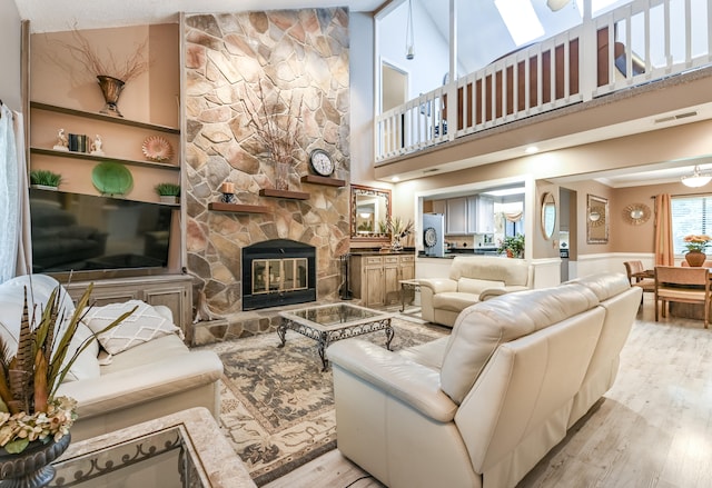 living room featuring a fireplace, high vaulted ceiling, and light hardwood / wood-style floors