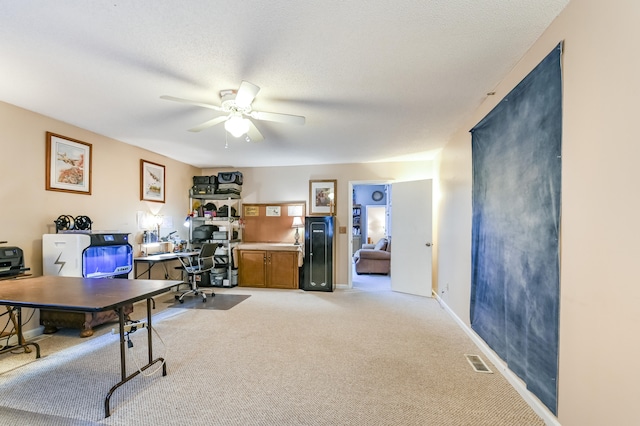 carpeted office featuring a textured ceiling and ceiling fan