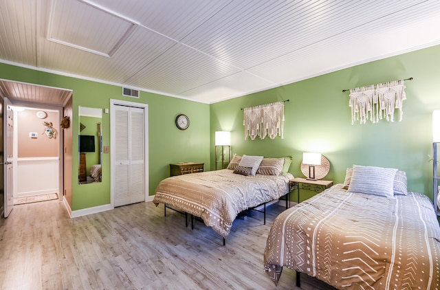 bedroom with light wood-type flooring, a closet, crown molding, and wooden ceiling