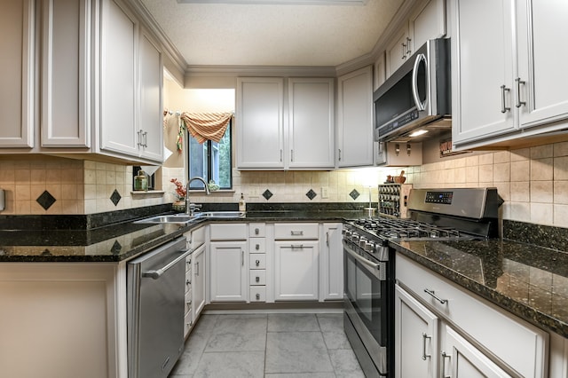 kitchen with a textured ceiling, stainless steel appliances, dark stone counters, and white cabinets