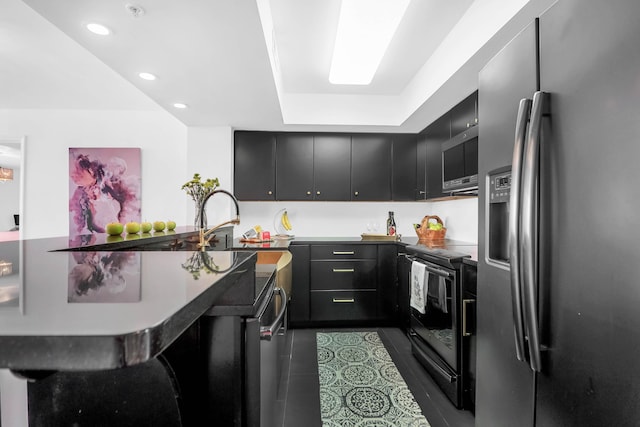 kitchen featuring a kitchen bar, a raised ceiling, kitchen peninsula, and appliances with stainless steel finishes