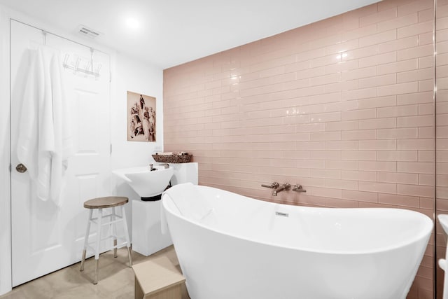 bathroom with a bathing tub and tile walls