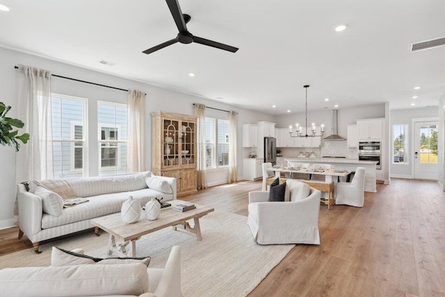 living room with light hardwood / wood-style floors and ceiling fan with notable chandelier