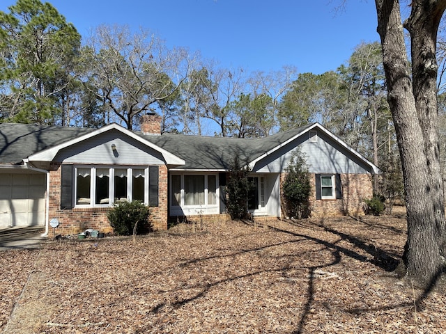 ranch-style home featuring brick siding, an attached garage, and a chimney