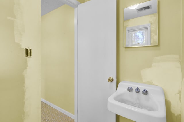 bathroom featuring baseboards, a sink, and visible vents