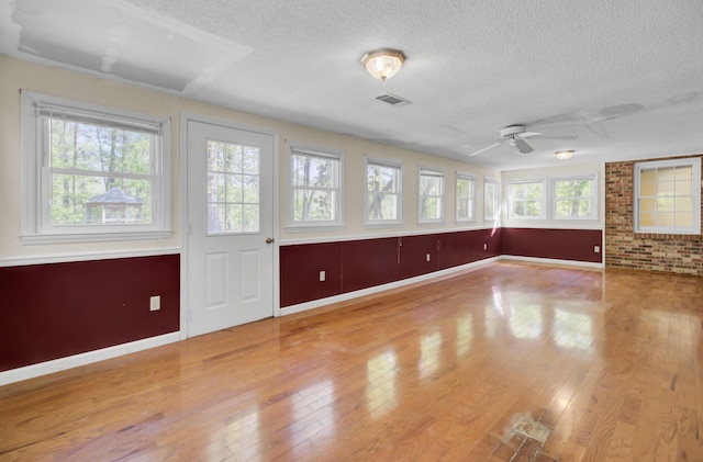 empty room with visible vents, baseboards, wood-type flooring, and a textured ceiling