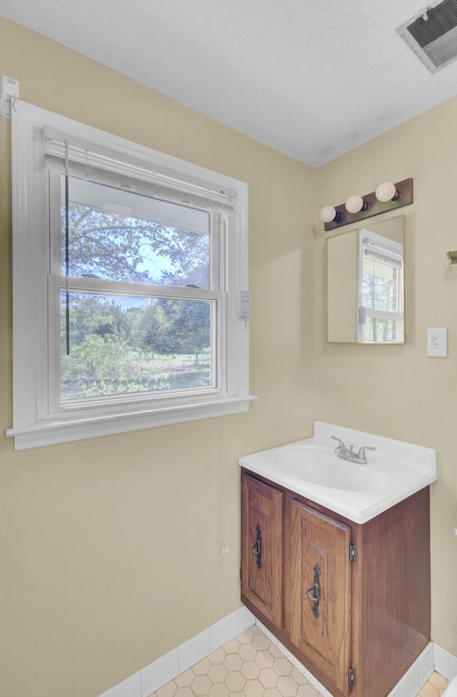 bathroom with tile patterned flooring, vanity, visible vents, and baseboards