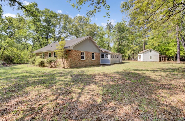 view of side of home with a yard, brick siding, and a sunroom