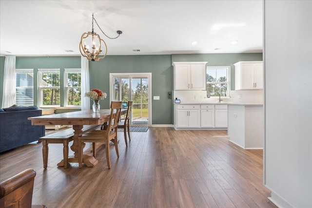 dining space featuring hardwood / wood-style flooring, an inviting chandelier, and sink