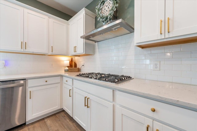 kitchen featuring white cabinetry, wall chimney exhaust hood, tasteful backsplash, appliances with stainless steel finishes, and light wood-type flooring