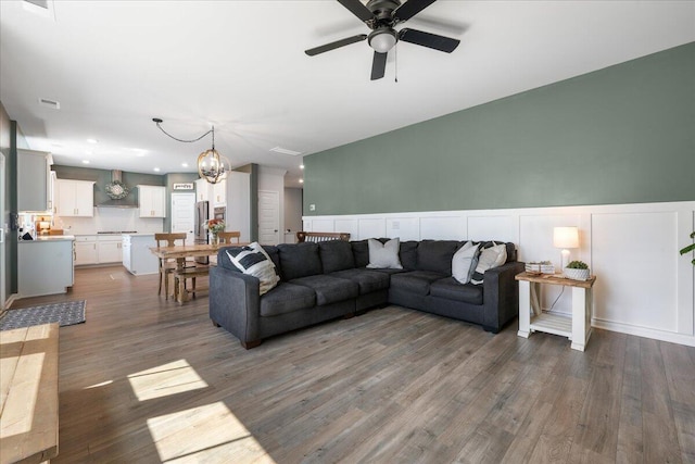 living room with ceiling fan with notable chandelier and dark hardwood / wood-style floors