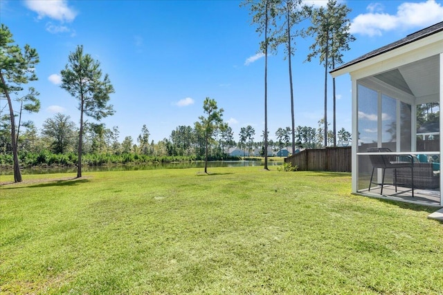 view of yard with a sunroom and a water view