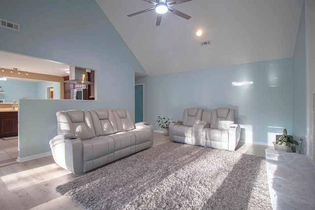 living room featuring light wood-type flooring, ceiling fan, sink, and high vaulted ceiling