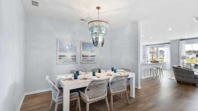 dining room with dark wood-type flooring and an inviting chandelier