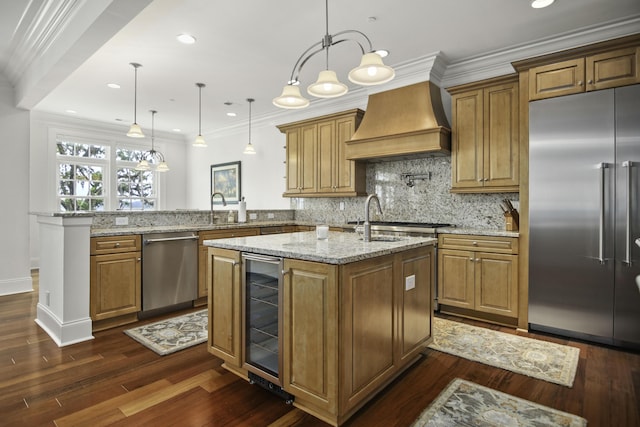 kitchen with stainless steel appliances, wine cooler, decorative light fixtures, kitchen peninsula, and wall chimney exhaust hood