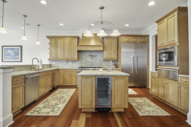 kitchen featuring wine cooler, built in appliances, sink, and hanging light fixtures