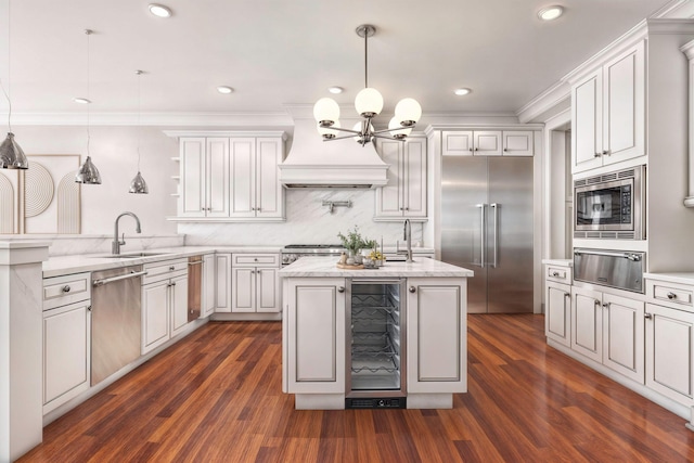 kitchen with sink, built in appliances, wine cooler, decorative light fixtures, and custom exhaust hood