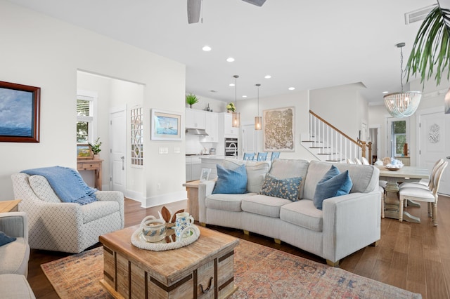 living room featuring a healthy amount of sunlight, a notable chandelier, and dark hardwood / wood-style floors