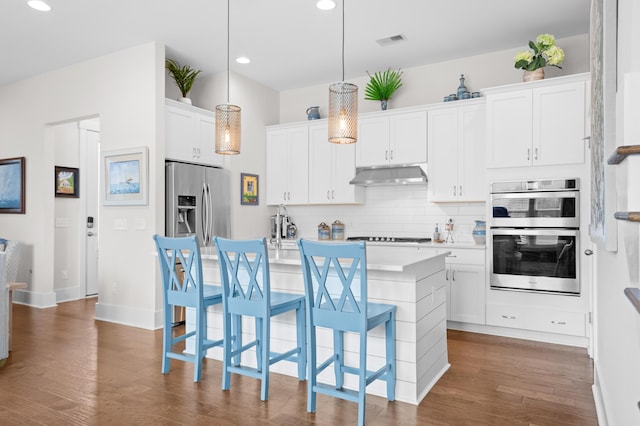 kitchen featuring hanging light fixtures, a breakfast bar area, stainless steel appliances, and white cabinets