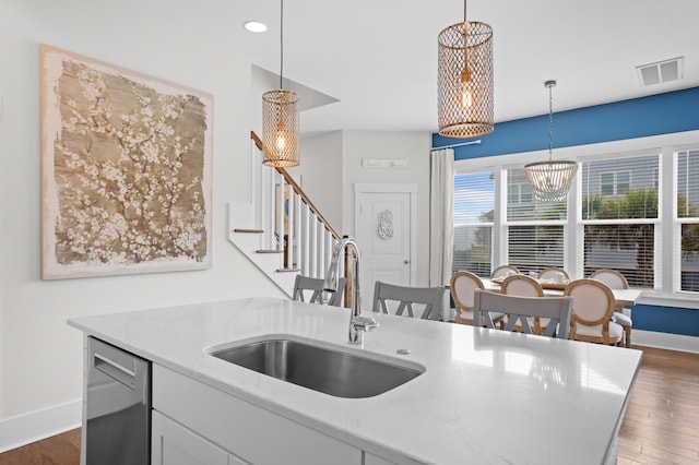 kitchen with dark hardwood / wood-style flooring, hanging light fixtures, stainless steel dishwasher, and sink