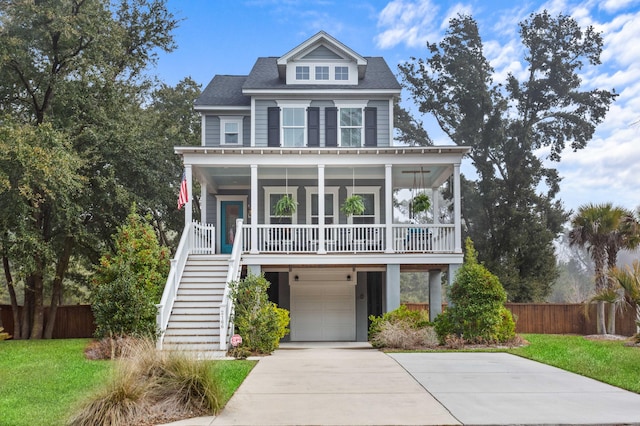 raised beach house with a garage, covered porch, and a front yard