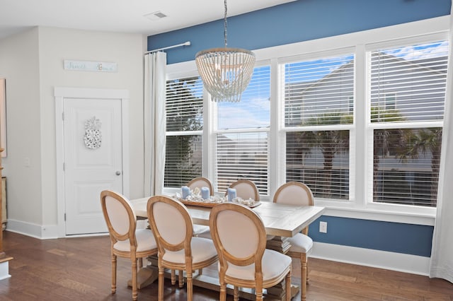 dining room with dark wood-type flooring and a notable chandelier