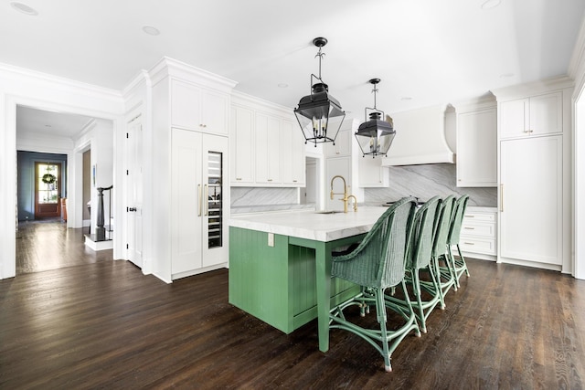 11 Dalton St, Daniel Island, SC 29492 - kitchen with custom exhaust hood, light countertops, a center island with sink, white cabinets, and decorative backsplash