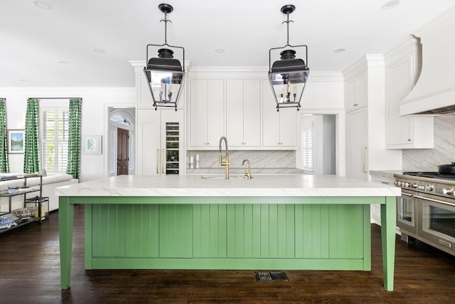 11 Dalton St, Daniel Island, SC 29492 - kitchen featuring range with two ovens, a sink, white cabinets, premium range hood, and crown molding