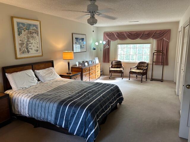 bedroom featuring a textured ceiling, ceiling fan, and carpet floors