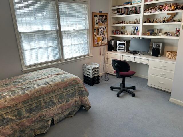 carpeted bedroom with built in study area