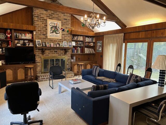 living room featuring a brick fireplace, light colored carpet, built in features, and wood walls