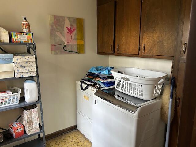 laundry room featuring cabinet space, washing machine and clothes dryer, light floors, and baseboards