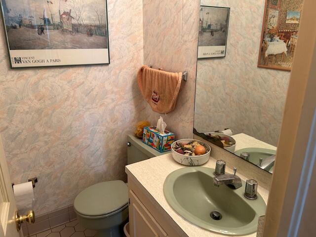 bathroom with tile patterned floors, toilet, vanity, and wallpapered walls
