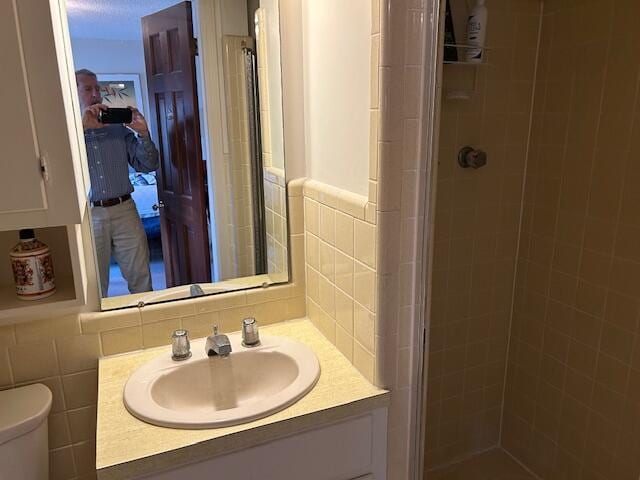 bathroom with toilet, a stall shower, vanity, and tile walls