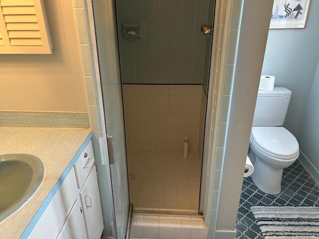 bathroom featuring vanity, baseboards, a stall shower, tile patterned floors, and toilet
