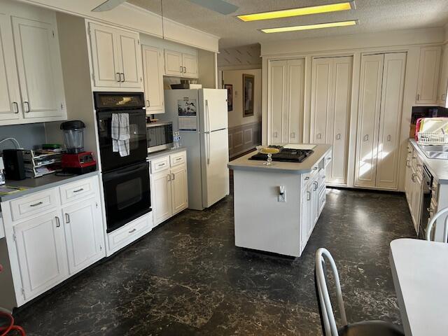 kitchen with white cabinets, light countertops, black appliances, and a kitchen island