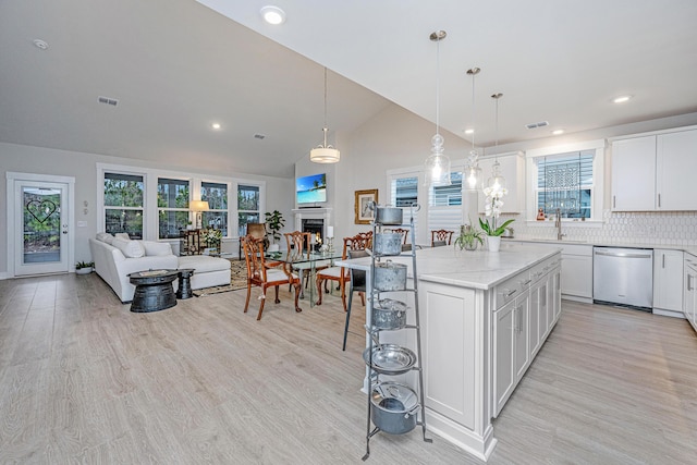 kitchen with pendant lighting, a breakfast bar area, white cabinetry, a kitchen island, and stainless steel dishwasher