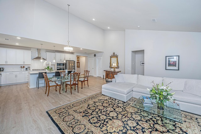 living room with high vaulted ceiling and light hardwood / wood-style flooring