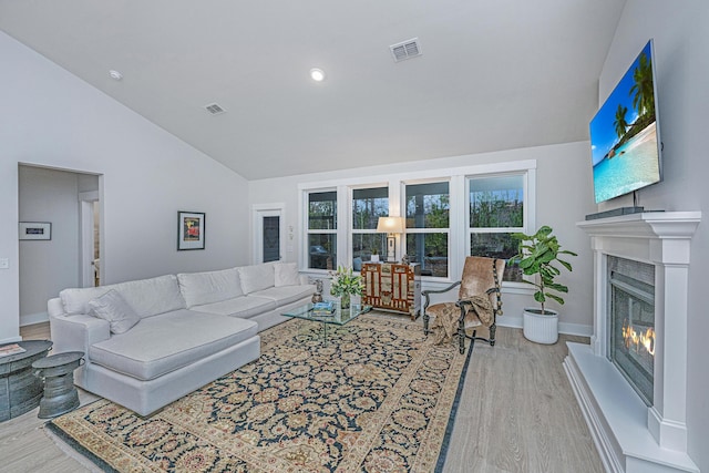 living room with high vaulted ceiling and light hardwood / wood-style flooring