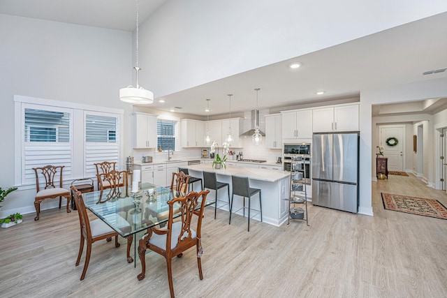 dining area featuring light hardwood / wood-style floors, sink, and a high ceiling