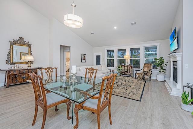 dining room featuring high vaulted ceiling and light hardwood / wood-style floors