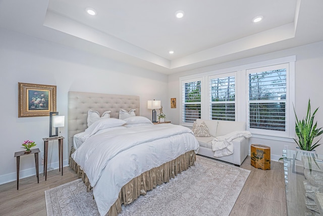 bedroom featuring a raised ceiling and light wood-type flooring