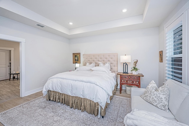 bedroom with a tray ceiling and light hardwood / wood-style floors