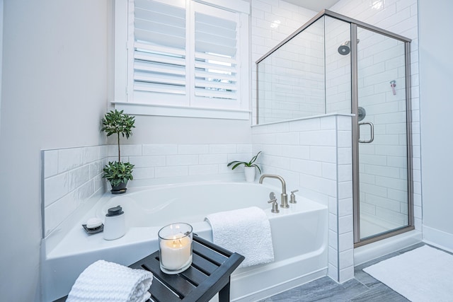 bathroom with shower with separate bathtub and wood-type flooring