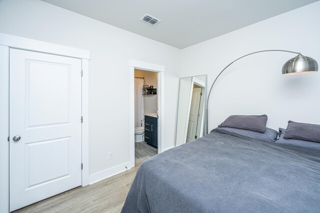 bedroom with ensuite bath and light hardwood / wood-style flooring