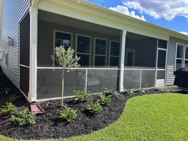view of side of home with a sunroom and a lawn