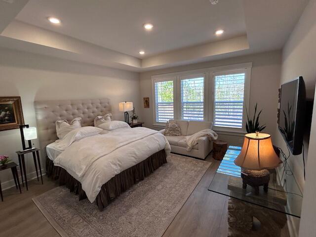 bedroom with a tray ceiling and hardwood / wood-style flooring