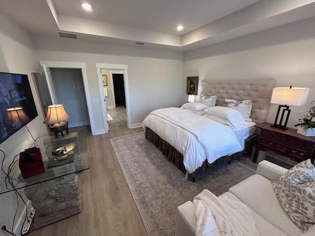 bedroom with a raised ceiling and hardwood / wood-style floors